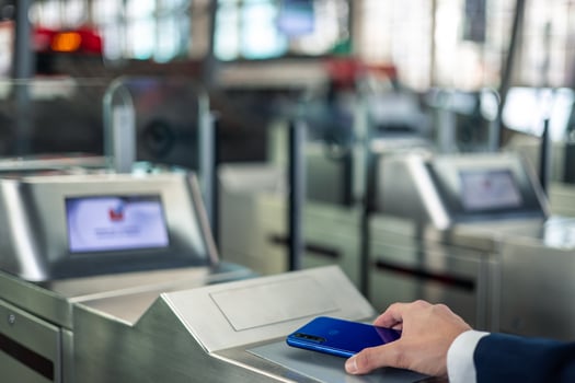 Close-up of a businessman using mobile contactless payment at metro station barriers photo