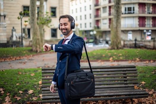 Businessman listening music with headphones and checking time on smartwatch photo