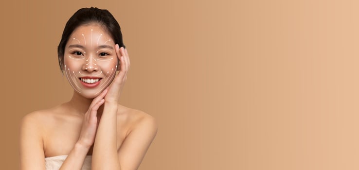 Asian woman enjoys her skin care routine, gently applying products to her face. She radiates happiness and calmness in a soothing, isolated setting with an empty background. photo