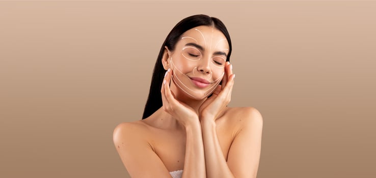 A woman indulges in her skincare routine, gently applying products to her face. This pampering moment captures her sense of tranquility and self-care against a soft, neutral background. photo