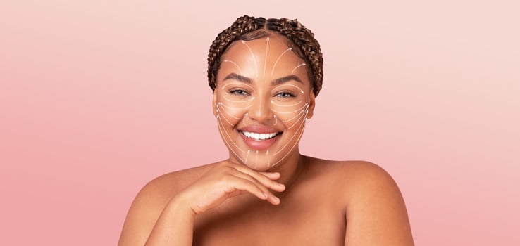 A joyful African American woman enjoys a pampering skincare routine with treatment lines drawn on her face. She radiates beauty and confidence in this tranquil setting, perfect for self-care moments. photo