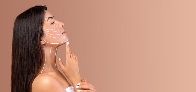 A lady is applying skin care products on her face, focusing on a relaxing beauty routine. She is in a tranquil setting with soft, neutral tones, creating a peaceful atmosphere for pampering. photo