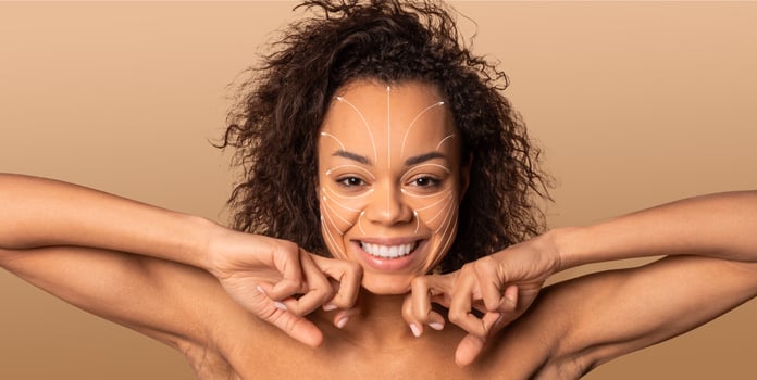 African American woman smiles while pampering herself with a skincare routine. She is in an isolated environment with a solid background, enjoying a moment of self-care and relaxation. photo