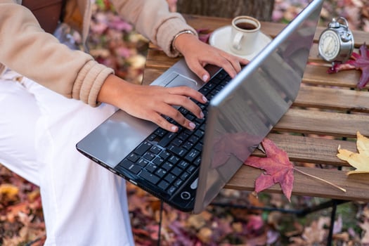 latin Woman working on laptop outdoors in autumn with coffee and alarm clock photo