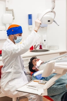 Dentist adjusting lamp while examining patient in clinic photo