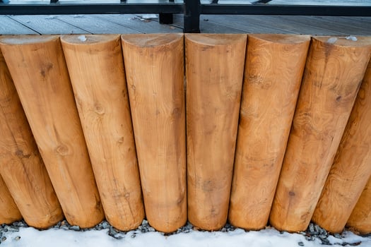 This captivating image features a closeup of a rustic wooden fence made of logs, covered in a soft layer of white snow, enhancing its natural charm and creating a picturesque winter scene photo