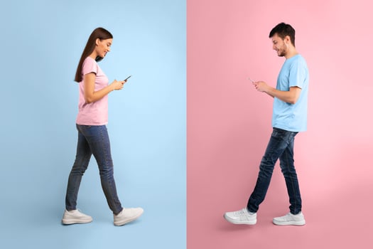 Communication, Technology And Lifestyle Concept. Full length portrait of smiling young couple using mobile phones, walking isolated over blue and yellow studio background, chatting photo