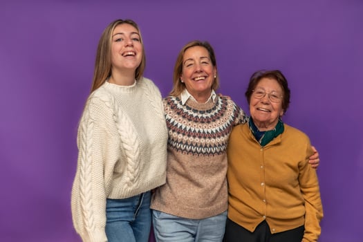 Three generations of women embracing and smiling on purple background photo