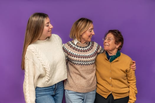 Three generations of women embracing on purple background photo