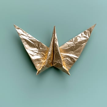 Gold origami bird on a teal background photo