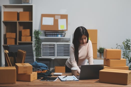 A woman working on her laptop in an office with boxes photo