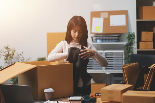 A woman is packing boxes in an office photo