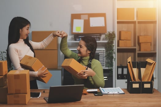 Two women are holding boxes in an office photo