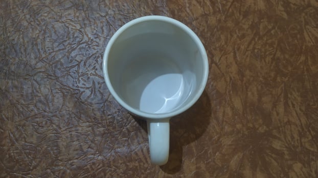 a white coffee cup sitting on top of a brown surface photo