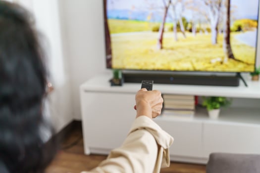 Elderly woman holding a remote control in front of a television photo