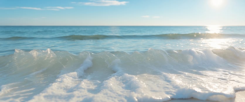 A wave is seen on the beach with the sun shining photo