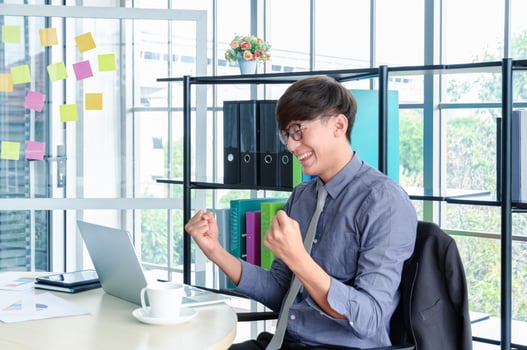 Portrait of young asian businessman triumphant and celebrate with arms up for job success in office photo