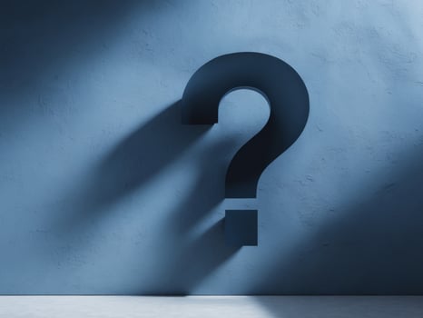 Textured blue wall with a shadowed large question mark symbol. photo