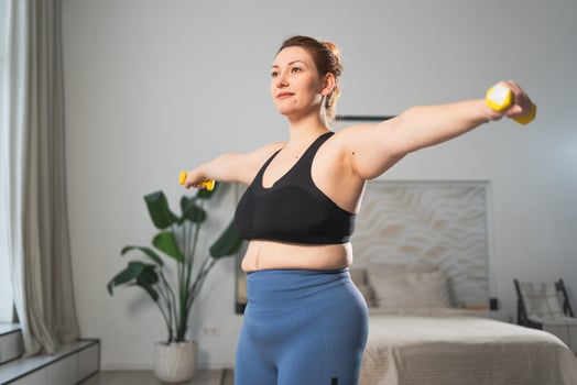 Fitness workout training. Woman picking up dumbbells. Plus size female doing sports exercise at home indoor. Girl in sportswear have workout weight training for weight loss. Sport and fitness photo