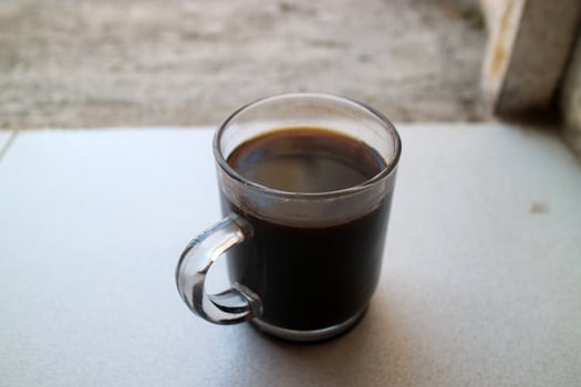 One glass of black coffee in a glass cup photographed from the side, during the day photo