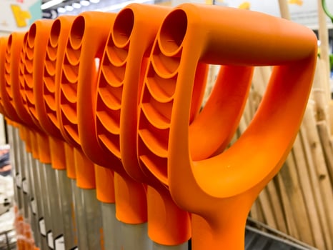 A vibrant collection of bright orange plastic shovels is neatly arranged in a straight line, creating a visually striking display of tools that can be used for various tasks photo