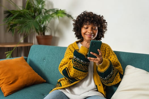 African girl holding smartphone touch screen typing scroll page at home. Woman with cell phone surfing internet using social media apps playing game. Shopping online Internet news cellphone addiction photo