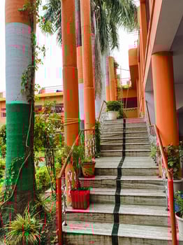 There are stairs that lead up to a building, and they are accompanied by a bright red railing that adds a pop of color, enhancing the overall appearance and accessibility of the structure photo