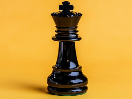 Black chess queen piece on yellow background photo