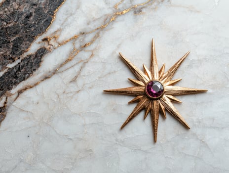 Gold starburst brooch with purple gemstone on marble background photo