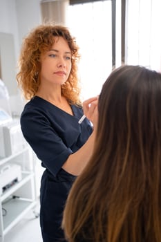 Female dermatologist examining anonymous client's skin in beauty salon photo