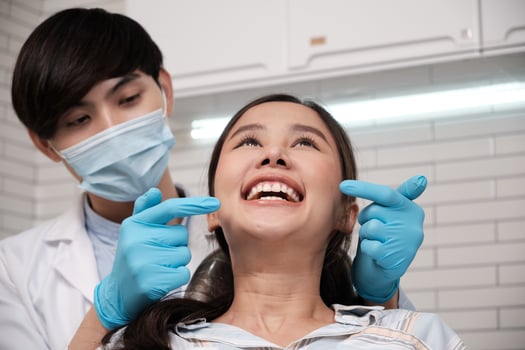 Close-up shot of beautiful Asian female face, white teeth, and cheerful in dentist's hand, dental treatment with tooth whitening and cleaning in doctor hospital clinic, oral hygiene healthcare. photo