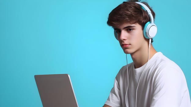 Focused and Determined Young Male Student Deeply Engaged in Academic Research and Study Using Laptop and Headphones on a Turquoise Blue Background photo