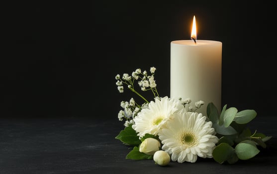 A white candle and flowers on a black background photo