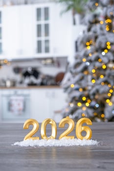 number 2026 on table in background of white kitchen with Christmas tree and Christmas decor with garland lights. Housing, interior, renovation, mortgage, rent in New Year photo