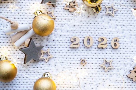 New Year wooden numbers 2026 on cozy festive white knitted background with sequins, stars, lights of garlands. Greetings, postcard. Calendar, cover photo