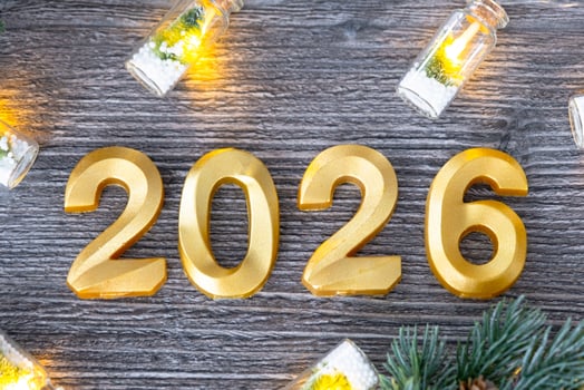 Happy New Year golden numbers 2026 on cozy festive grey wooden background with Christmas tree, snow, lights of garlands. Greetings, postcard. photo