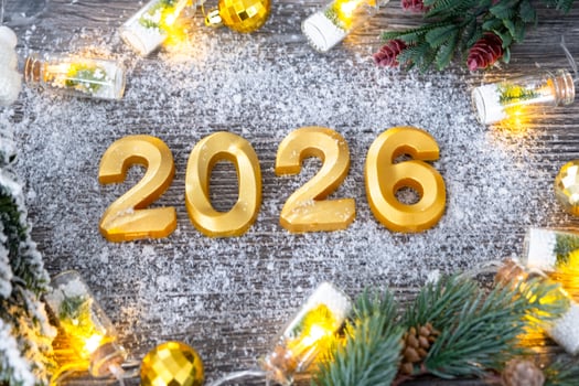 Happy New Year golden numbers 2026 on cozy festive grey wooden background with Christmas tree, snow, lights of garlands. Greetings, postcard. Calendar, photo