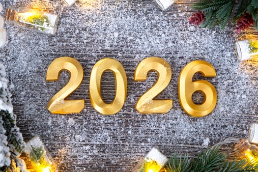 Happy New Year golden numbers 2026 on festive grey wooden background with Christmas tree, snow, lights of garlands. Greetings, postcard. Calendar, cover photo