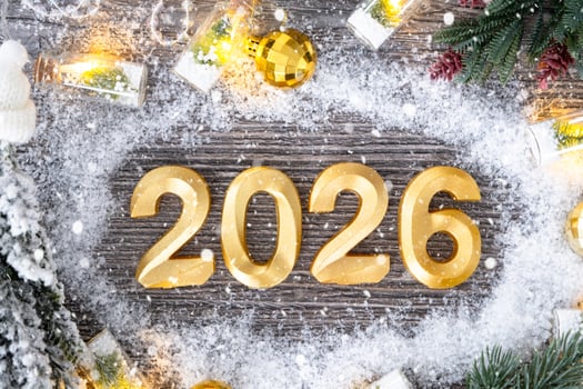 Happy New Year golden numbers 2026 on cozy grey wooden background with Christmas tree, snow, lights of garlands. Greetings, postcard. Calendar photo