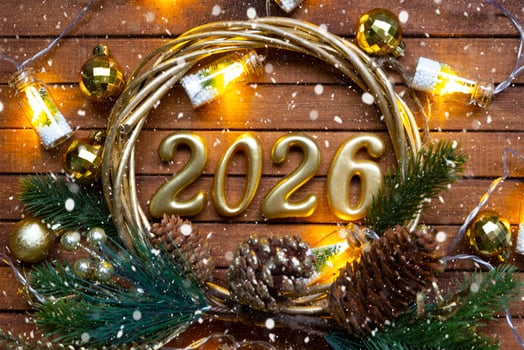 Happy New Year wooden numbers 2026 on cozy festive brown wooden background in a wreath with sequins, snow, lights of garlands. Greetings, postcard. Calendar, cover photo