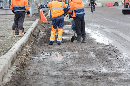 A group of road workers install road curbs along the roadway. photo