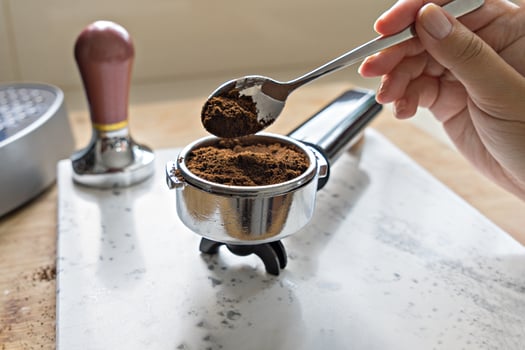 Female hand puts fresh ground coffee in portafilter photo