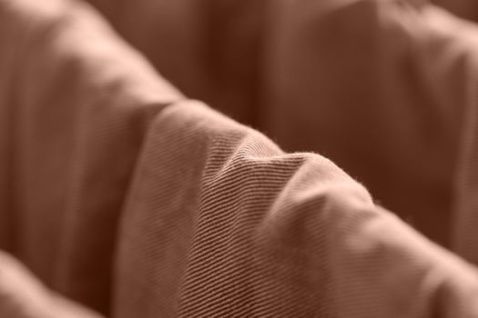 Close up view of wavy brown corduroy fabric texture in soft focus with warm lighting. photo