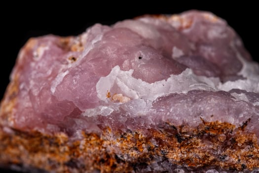 Macro pink Smithsonite mineral stone on microcline on black background close up photo