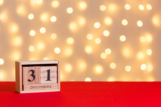 wooden calendar 31 december on red background and lights background close up photo