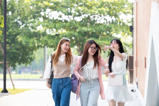 Happy Asian teenager female college student holding book and looking at nature outdoors at university Prepare for class photo