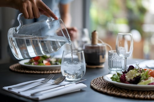 Water pours from jug into glass, creating serene dining ambiance photo