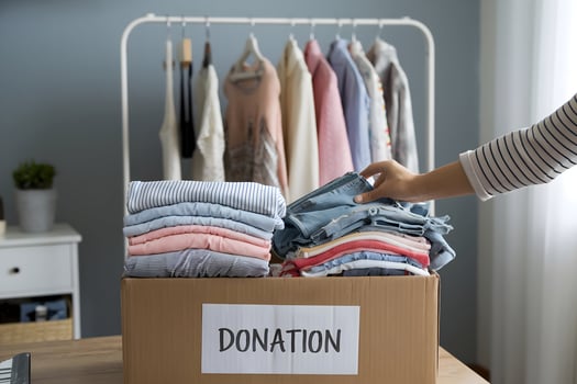 Donation box holds clothes as hand reaches to pick an item photo