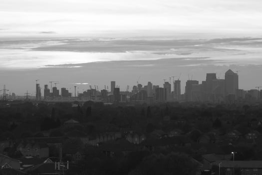 Canary Wharf emerging from the suburban houses in London at sunset, black and white photography photo