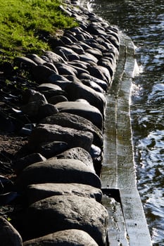 A Serene Riverbank Featuring Smooth Stones and Reflective, Sparkling Water Beneath the Sun photo